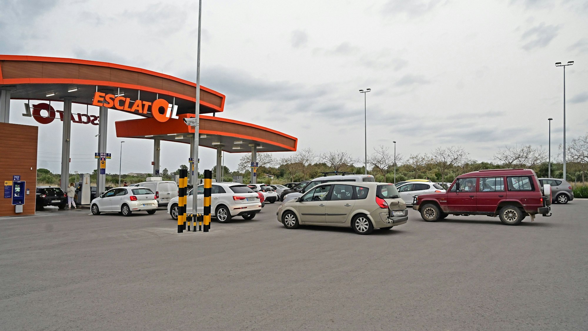 Tankstelle mit Fahrzeugen und Personen
