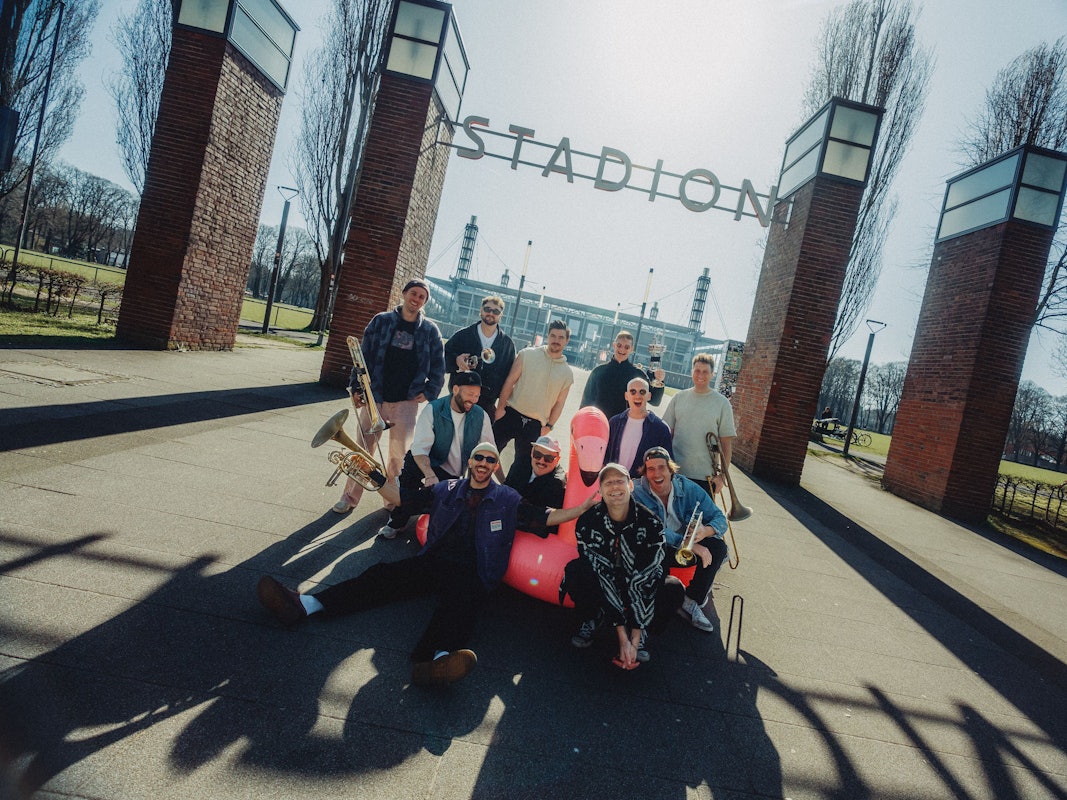 Die Band Querbeat posiert vor dem Rhein-Energie-Stadion in Köln
