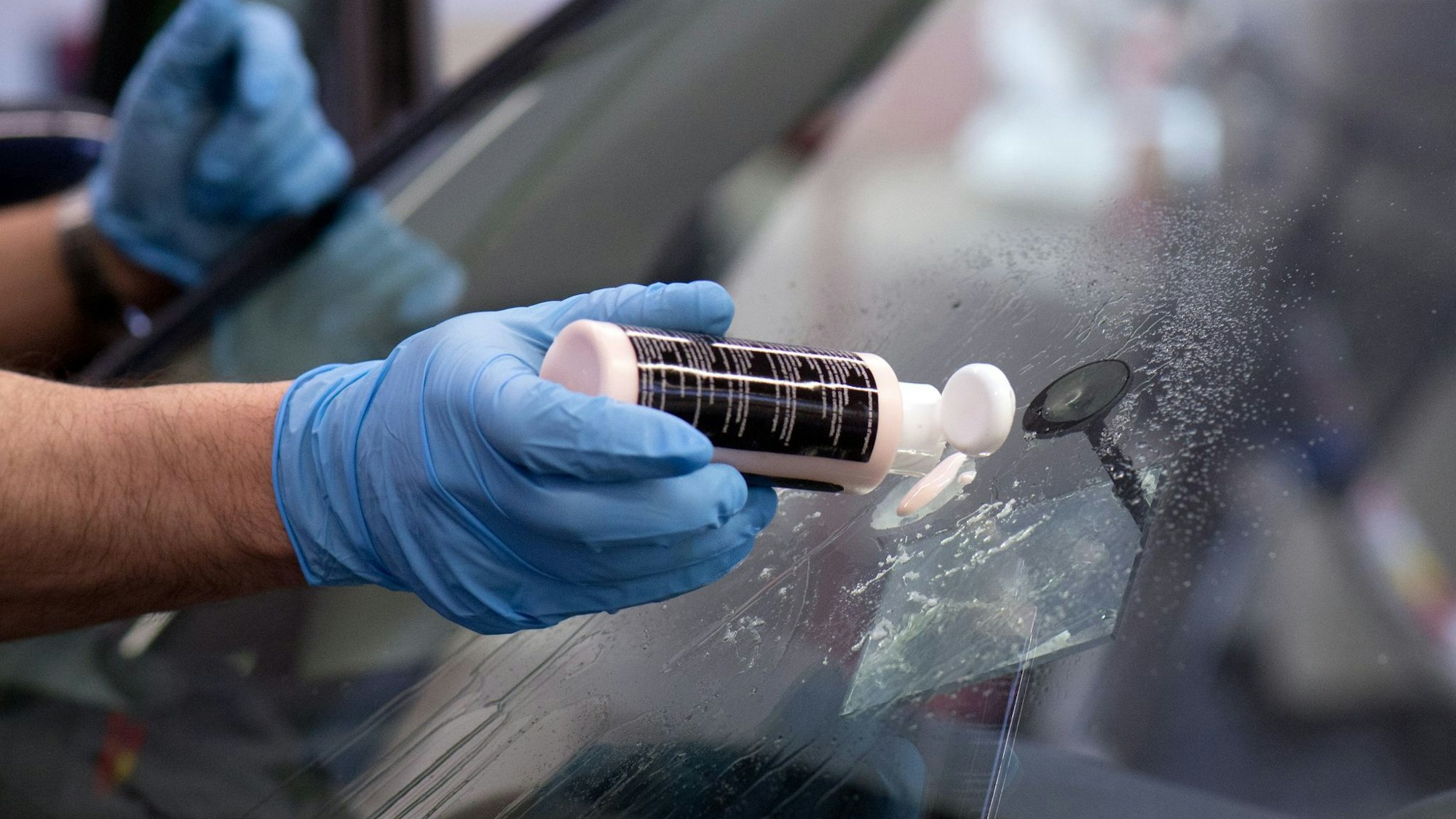 Ein Steinschlagschaden in der Frontscheibe wird repariert