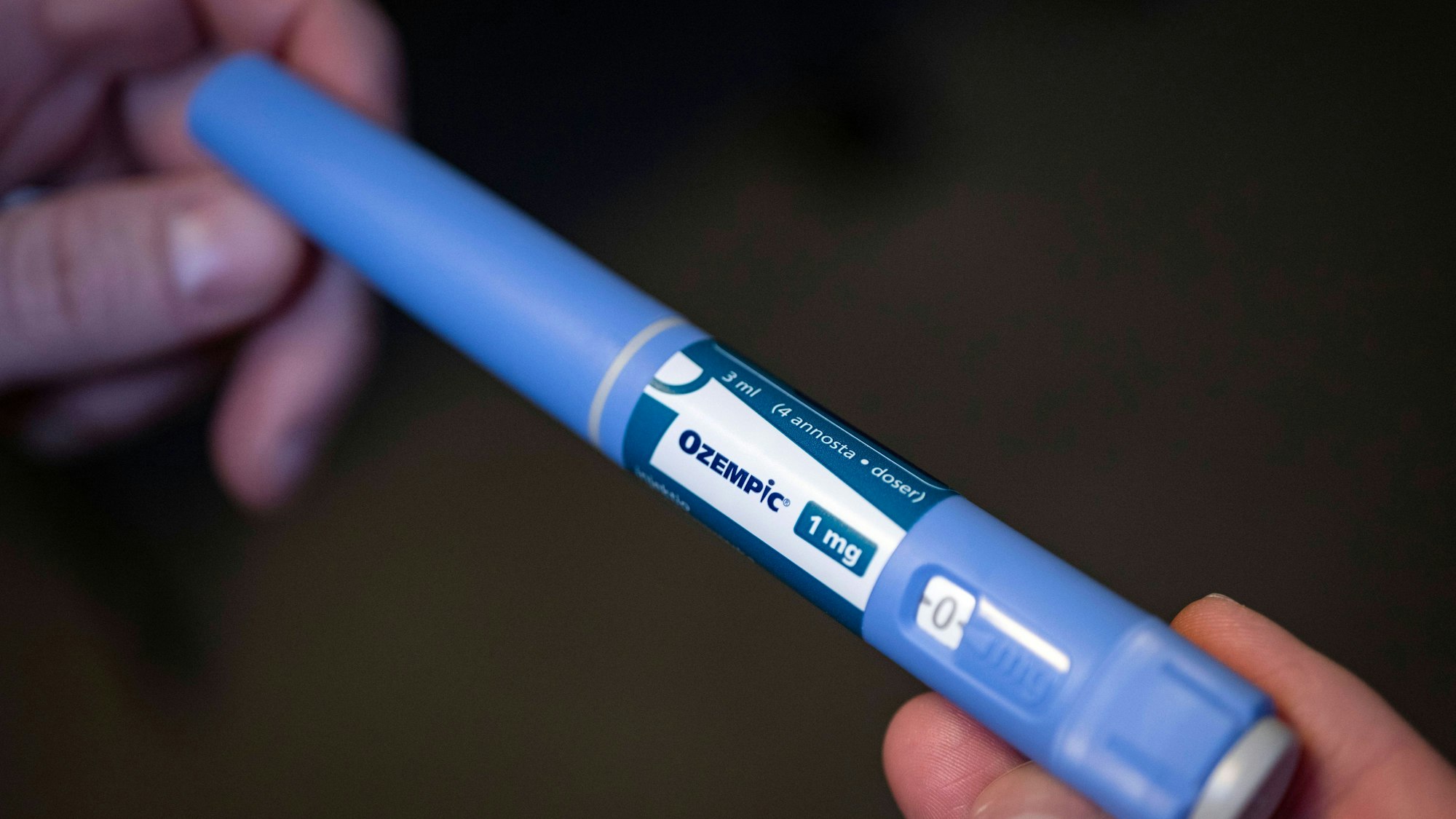 Hände halten einen Injektionspen