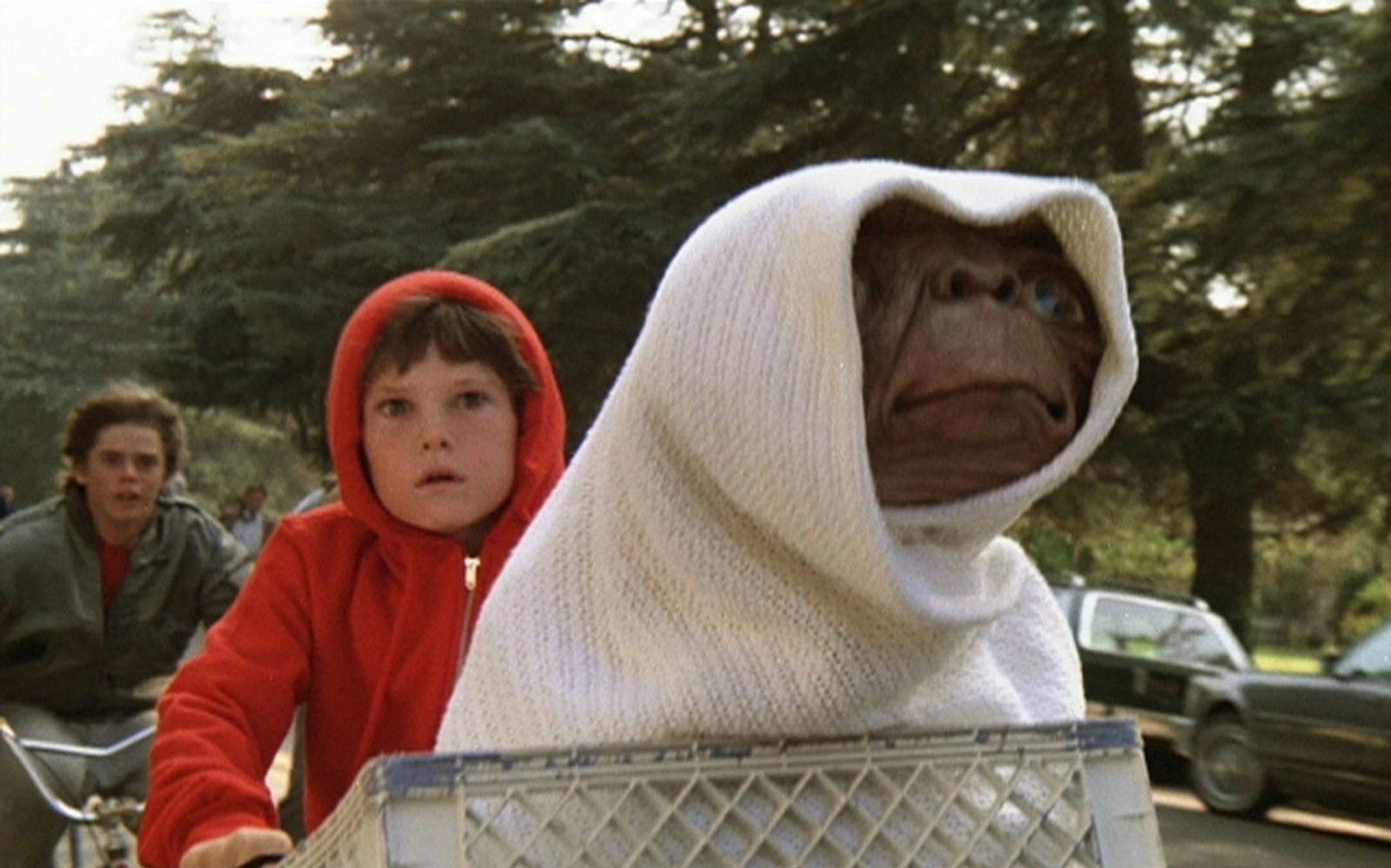Auch er zählte zum (erweiterten) Freundeskreis der Hauptfigur: Tyler (C. Thomas Howell, links) ist dabei, als Elliott (Henry Thomas, Mitte) seinen Freund E.T. auf einem BMX-Rad zu seinem Raumschiff bringt. (Bild: Universal Pictures)