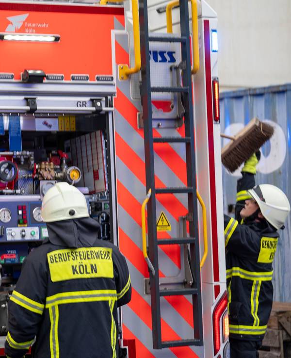 Zwei Feuerwehrmänner stehen am Einsatzfahrzeug.