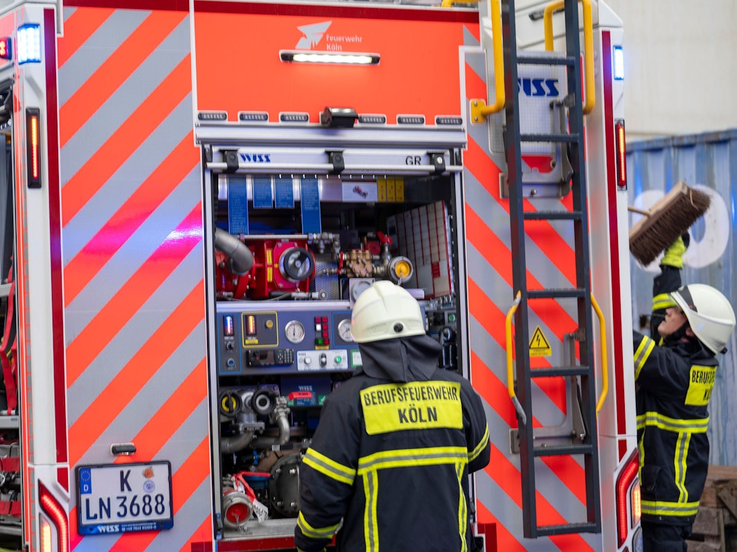 Zwei Feuerwehrmänner stehen am Einsatzfahrzeug.