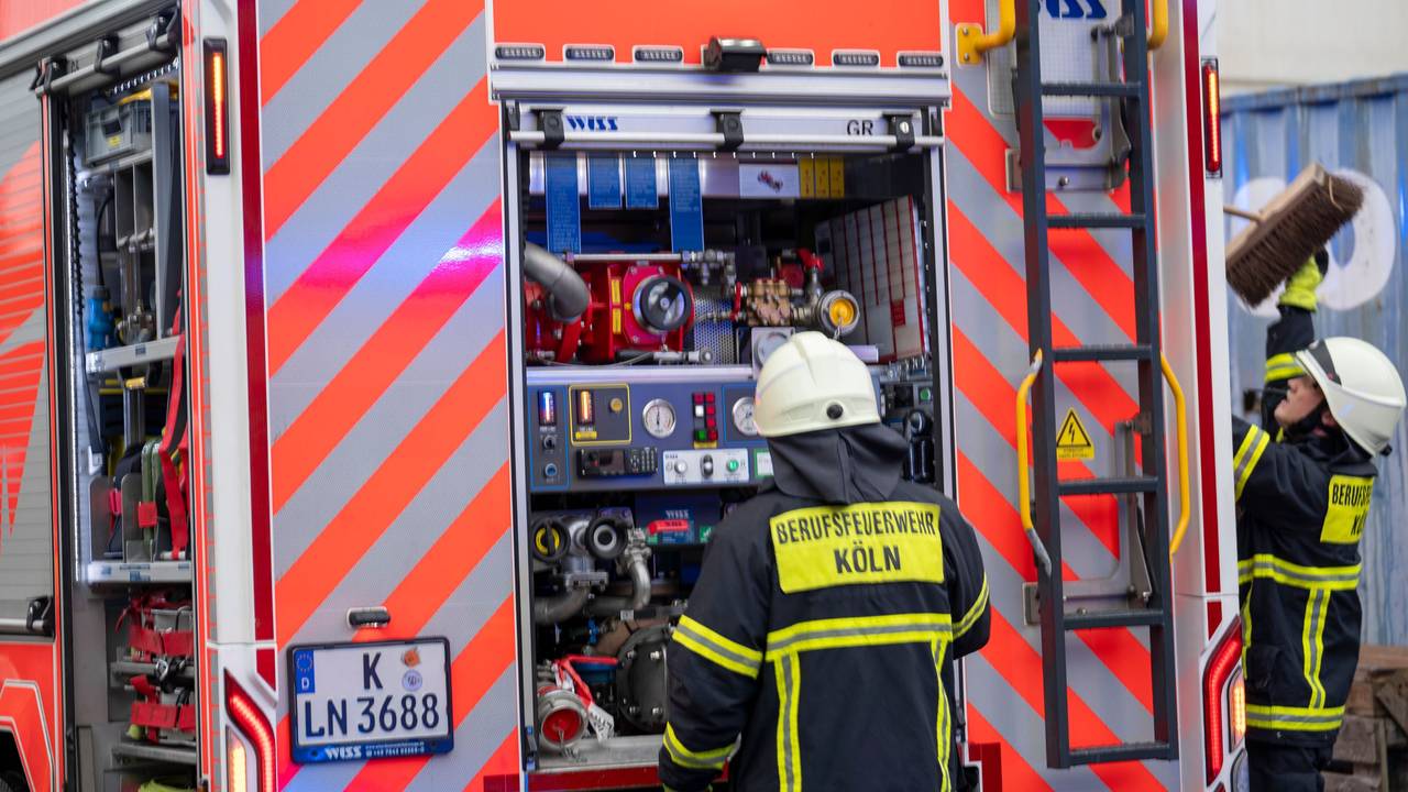 Zwei Feuerwehrmänner stehen am Einsatzfahrzeug.
