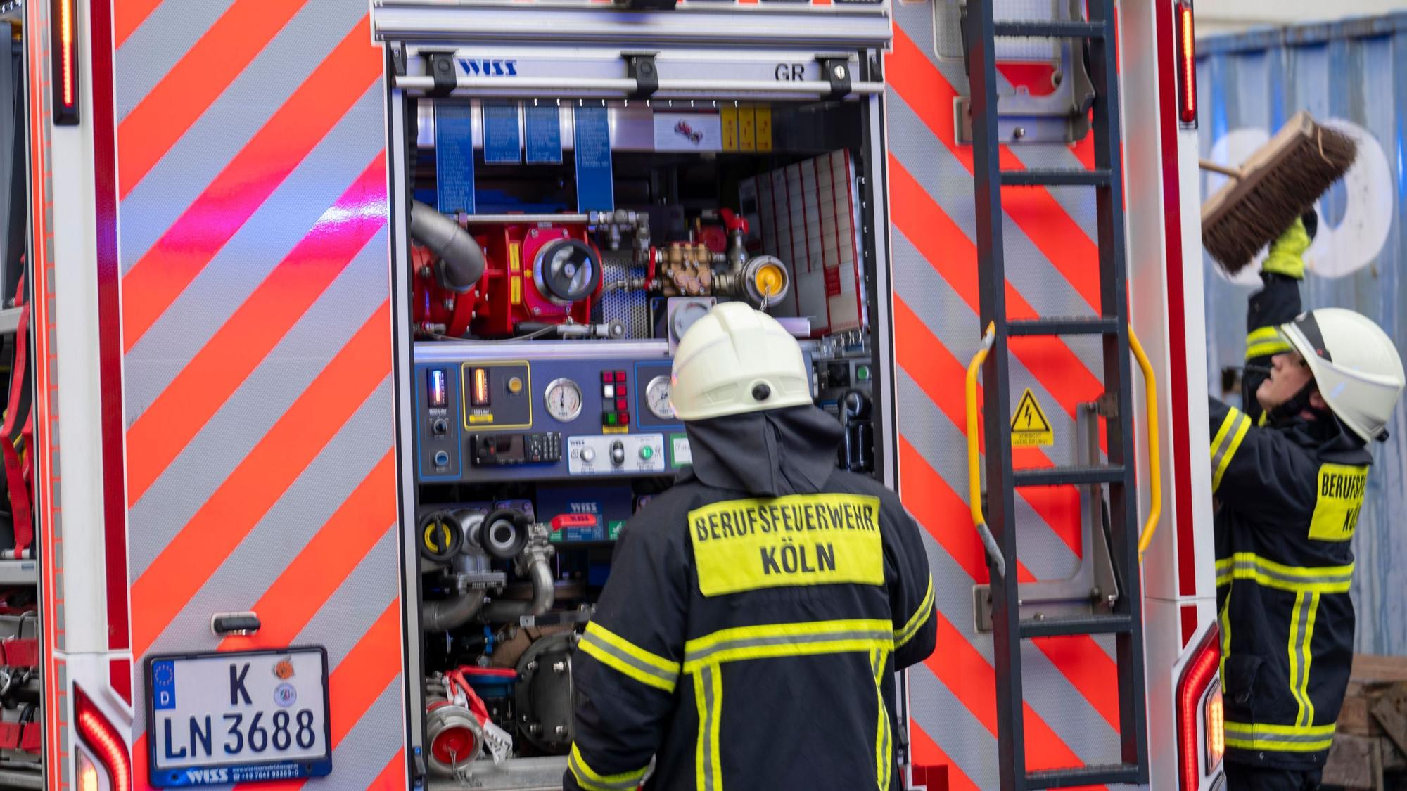 Zwei Feuerwehrmänner stehen am Einsatzfahrzeug.