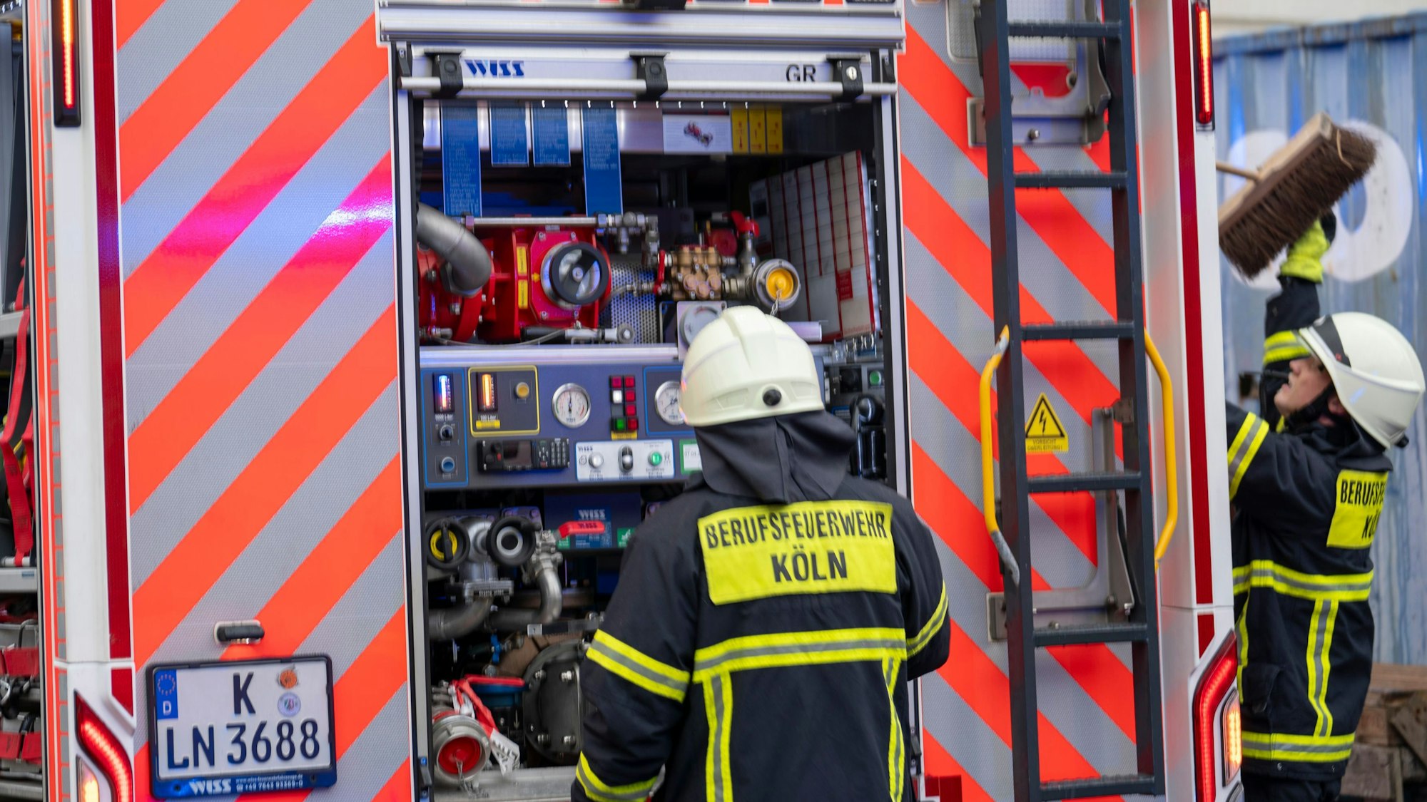 Zwei Feuerwehrmänner stehen am Einsatzfahrzeug.