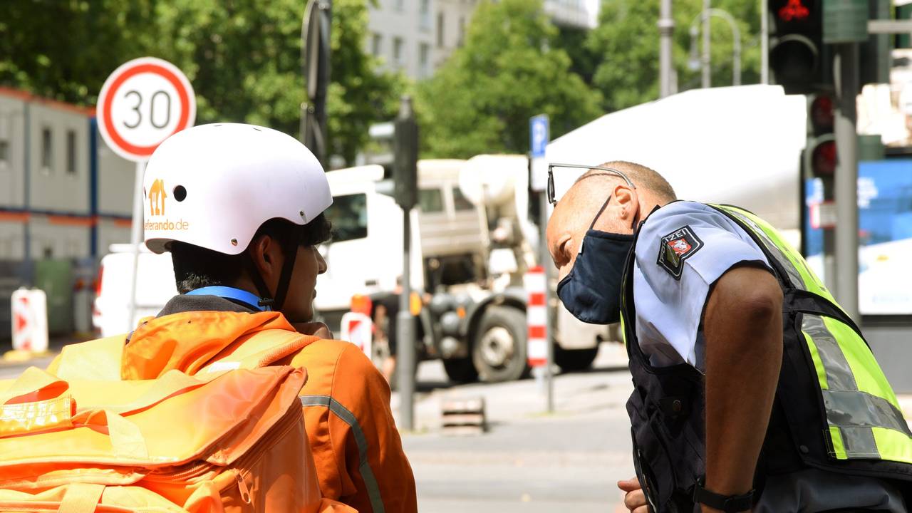 Ein Polizist spricht mit einem Essenslieferanten.