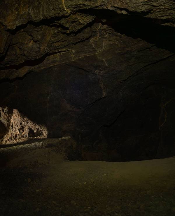 Frau erkundet dunkle unterirdische Höhle.