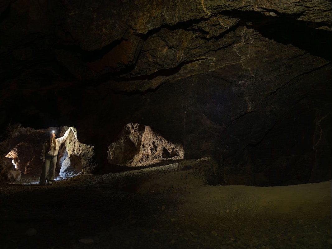 Frau erkundet dunkle unterirdische Höhle.