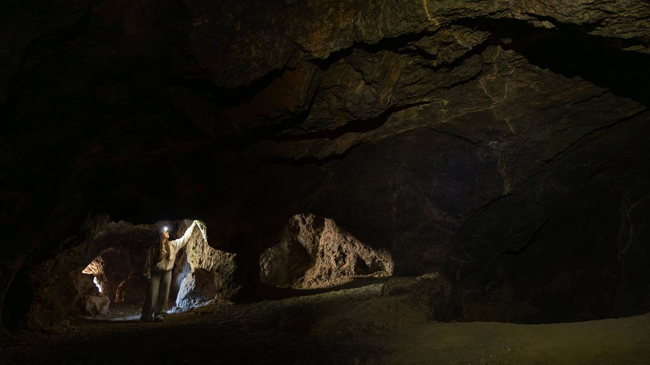 Frau erkundet dunkle unterirdische Höhle.