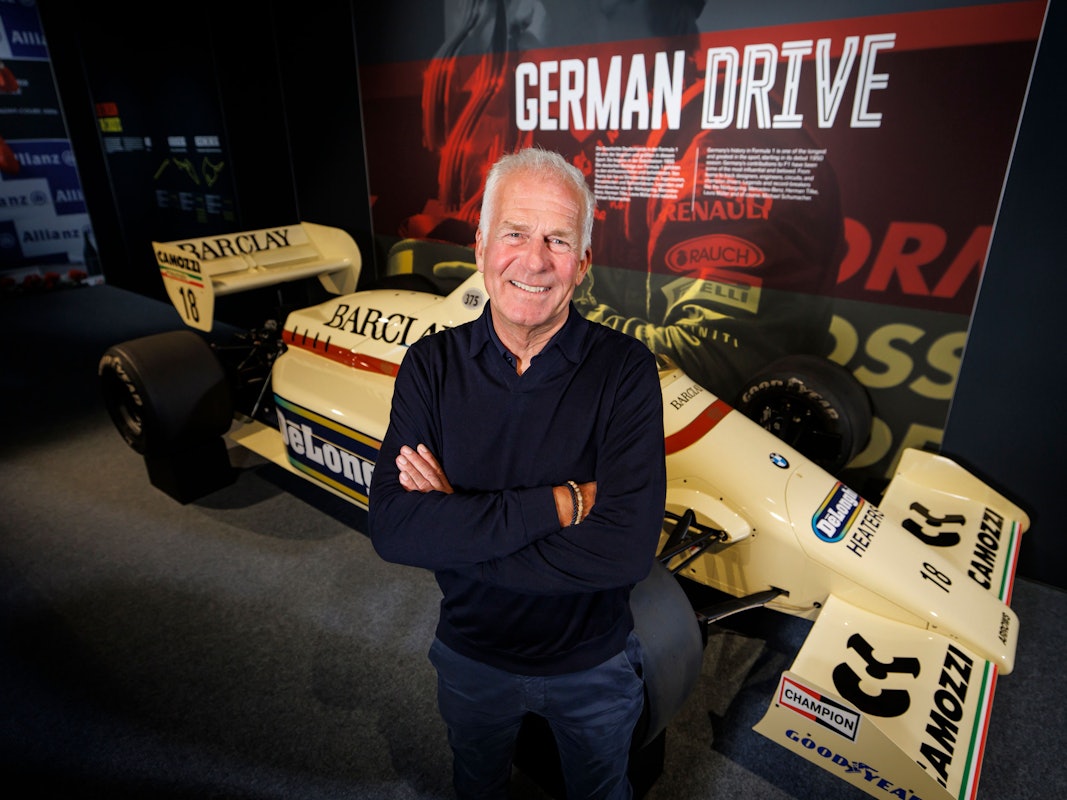 Christian Danner posiert in Oberhausen vor einem F1-Auto.