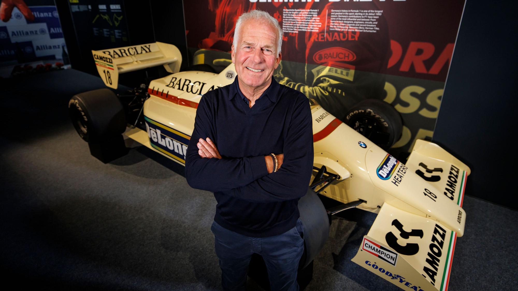 Christian Danner posiert in Oberhausen vor einem F1-Auto.