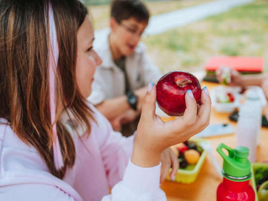Mädchen hält Apfel beim Mittagessen