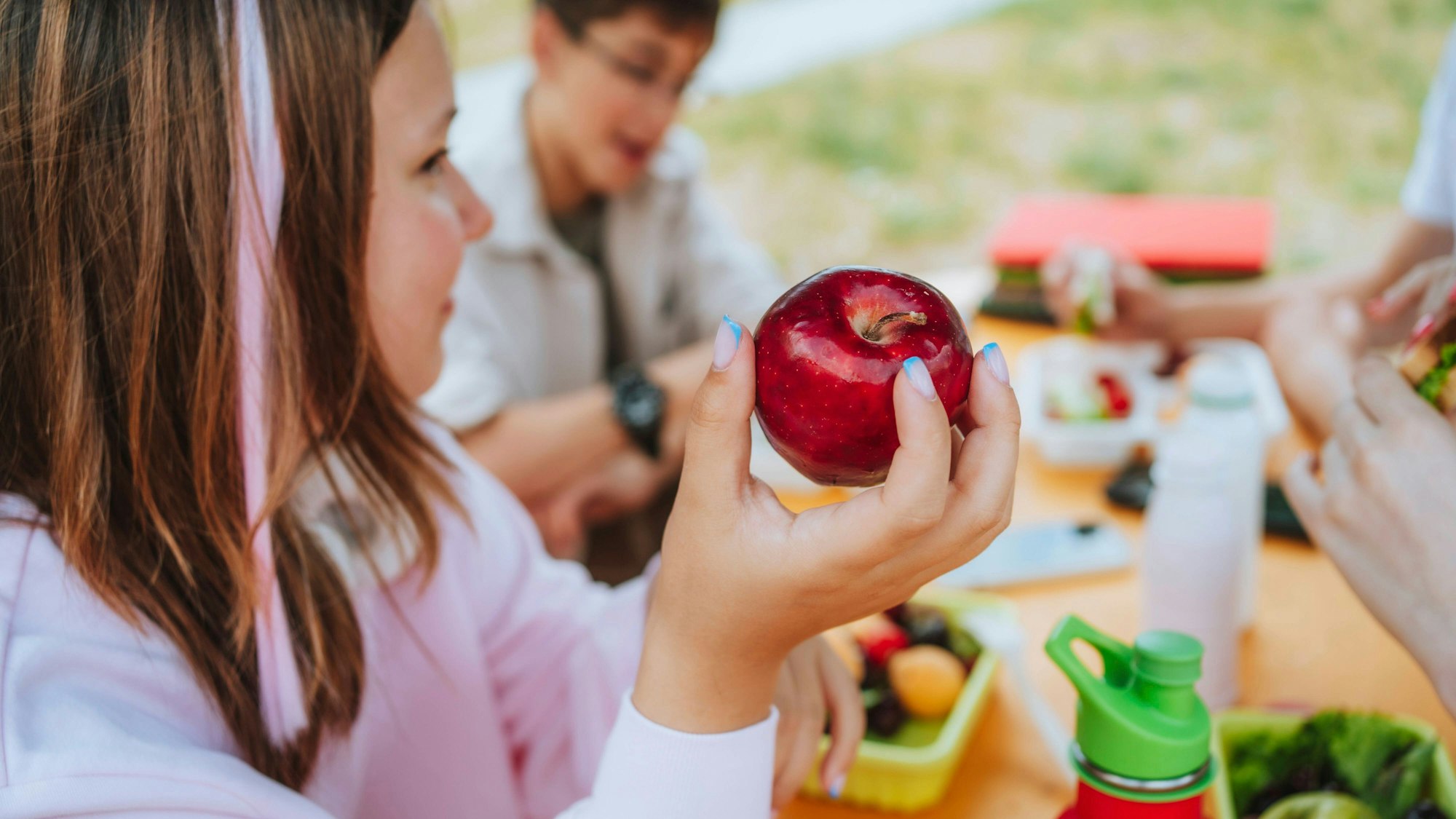 Mädchen hält Apfel beim Mittagessen
