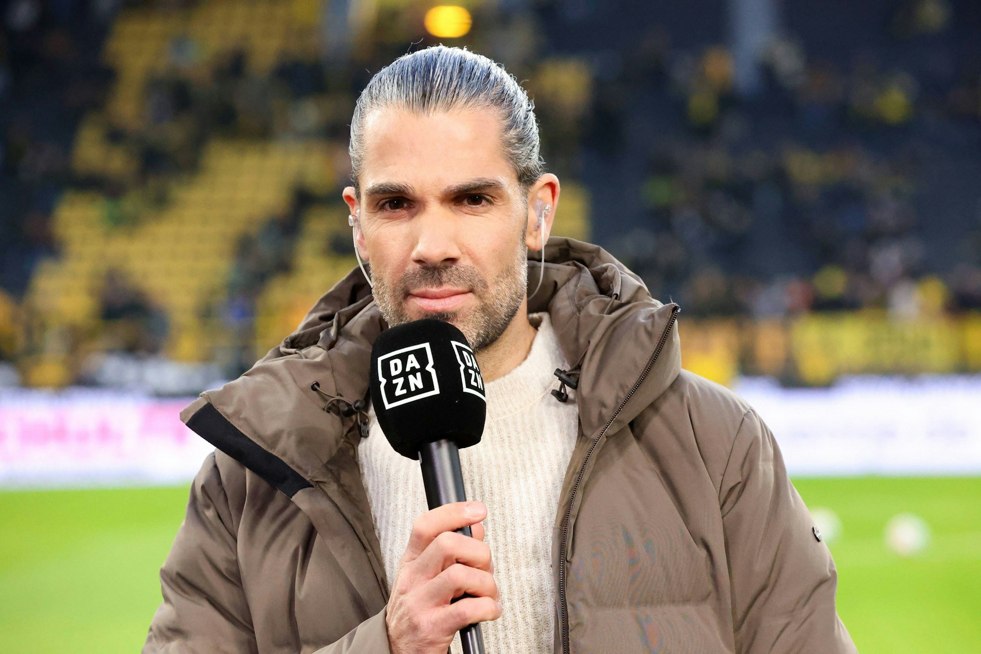 Daniel Herzog steht mit DAZN-Mikro im Stadion.