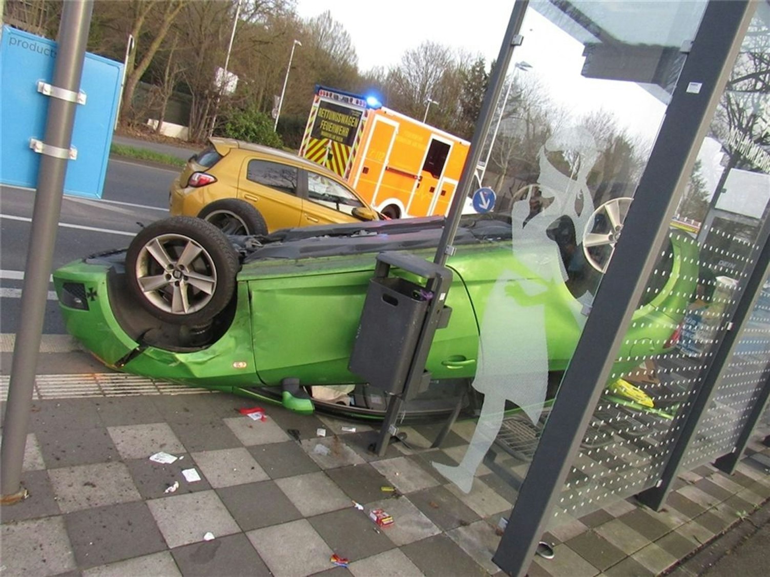 Ein demoliertes Auto liegt auf dem Dach in einer zerstörten Bushaltestelle.