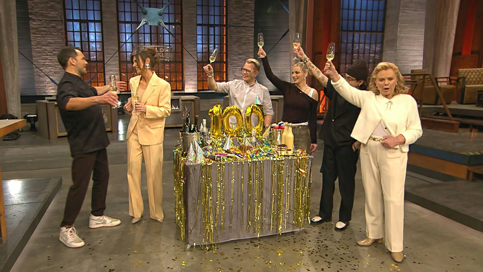 „Stößchen!“ Zu Beginn von „Grill den Henssler“ (VOX) überraschte Gastgeber Steffen Henssler Moderatorin Laura Wontorra. Zu Ehren ihrer 100. Sendung gibt's einen Geschenkewagen „voll mit deinen Grundnahrungsmitteln: Prosecco, Dosenbier, Eierlikör“. (Bild: RTL)