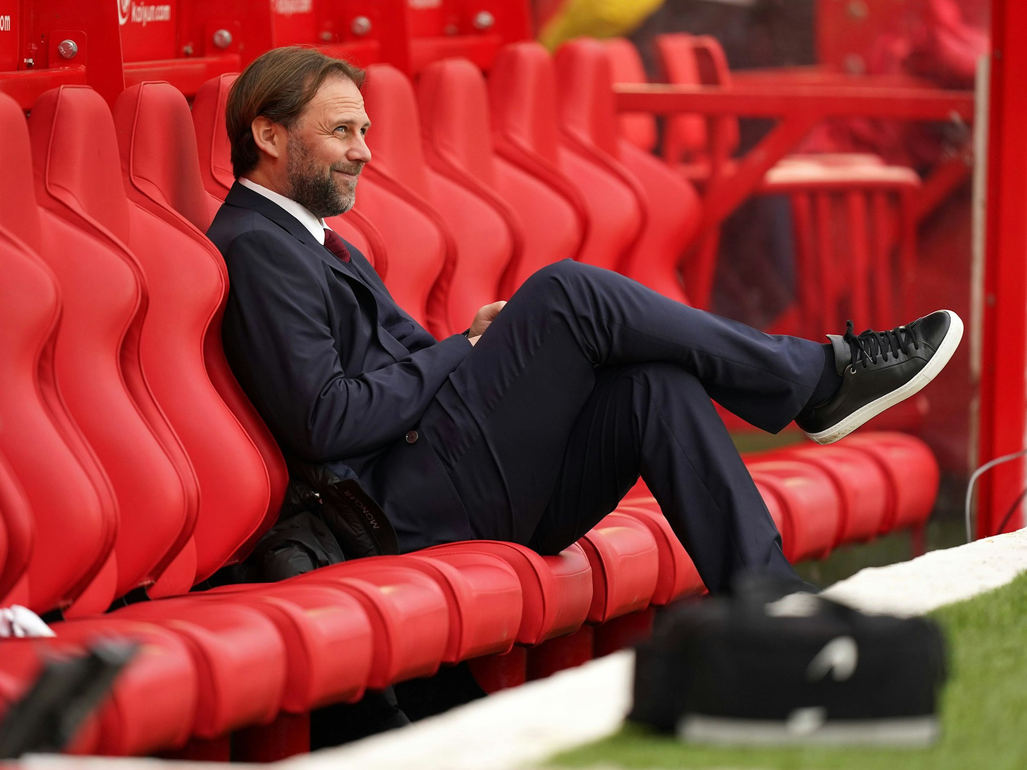 Tim Steidten sitzt lächelnd auf der leeren Ersatzbank.