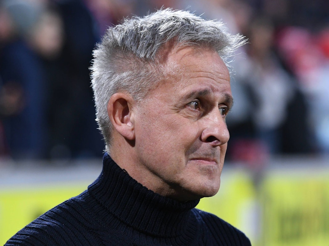 Pierre Littbarski in Nahaufnahme, er steht im Stadion, nur sein Gesicht und die Schultern sind abgebildet.