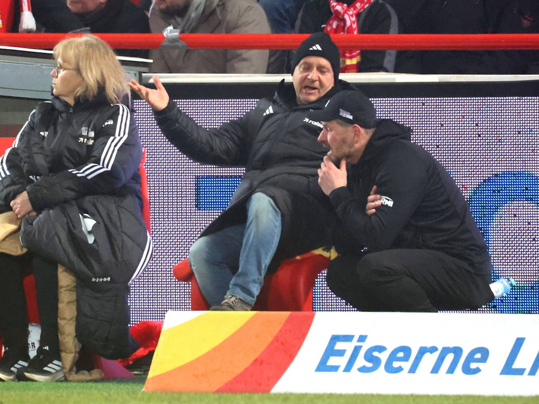 Trainer Steffen Baumgart hockt zusammen mit Union-Geschäftsführer Horst Heldt am Arande eines Bundesligaspiels.