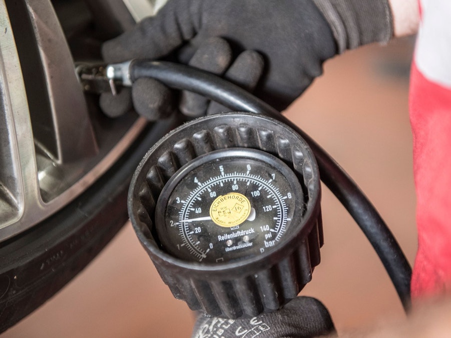 Kfz-Mechatroniker prüft den Reifendruck eines reifens