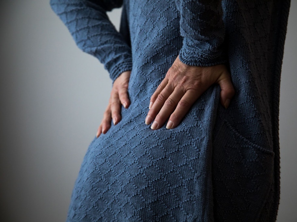 Frau hält sich den schmerzenden Rücken