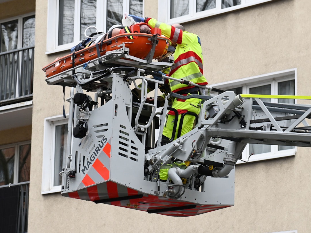Ein Patient liegt auf einer Trage auf der Drehleiter, neben ihm ein Notarzt.