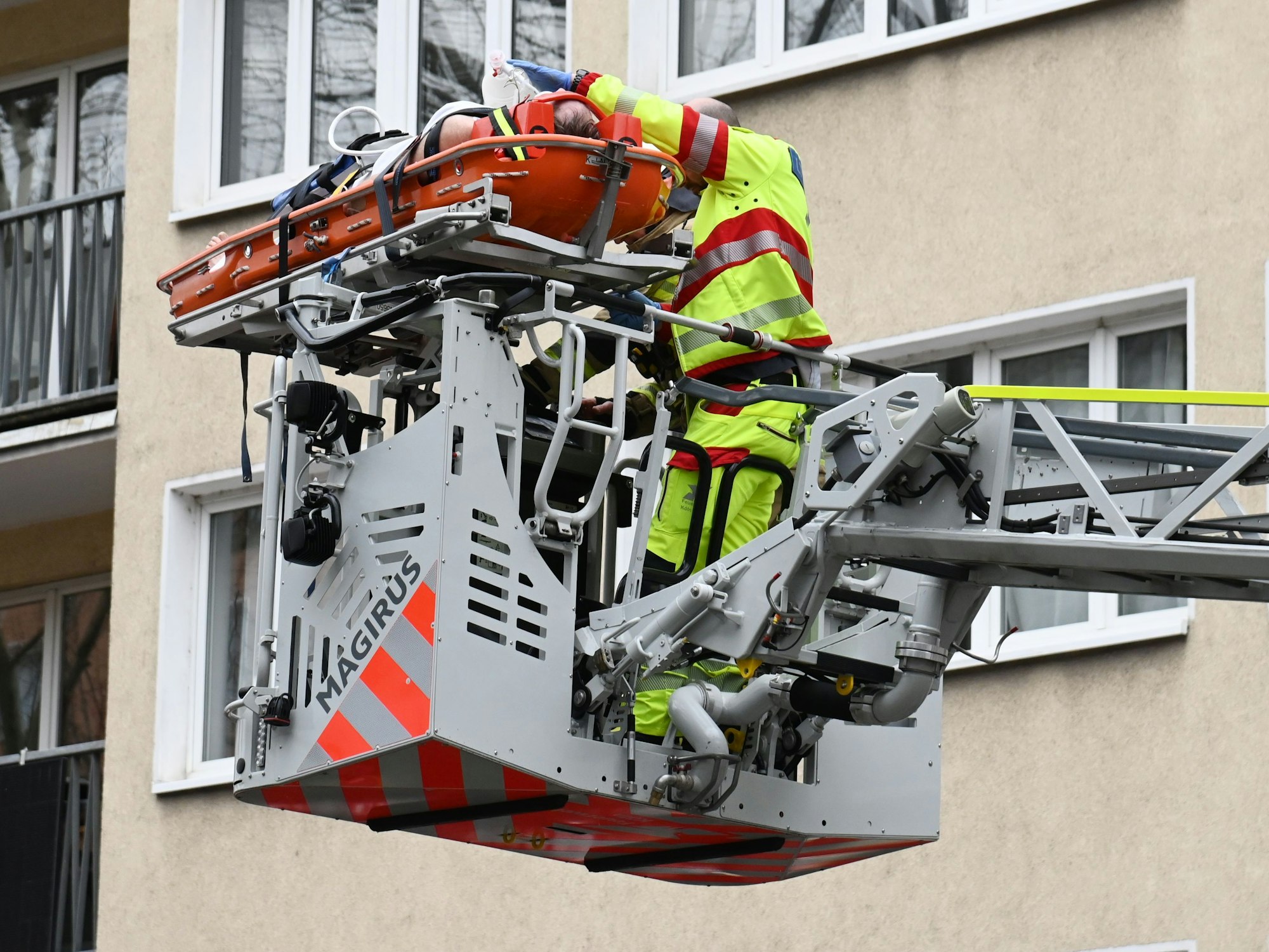 Ein Patient liegt auf einer Trage auf der Drehleiter, neben ihm ein Notarzt.
