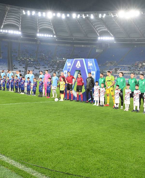 Die Mannschaften stehen vor dem Spiel aufgereiht, auf der Tribüne dahinter sind kaum Fans.