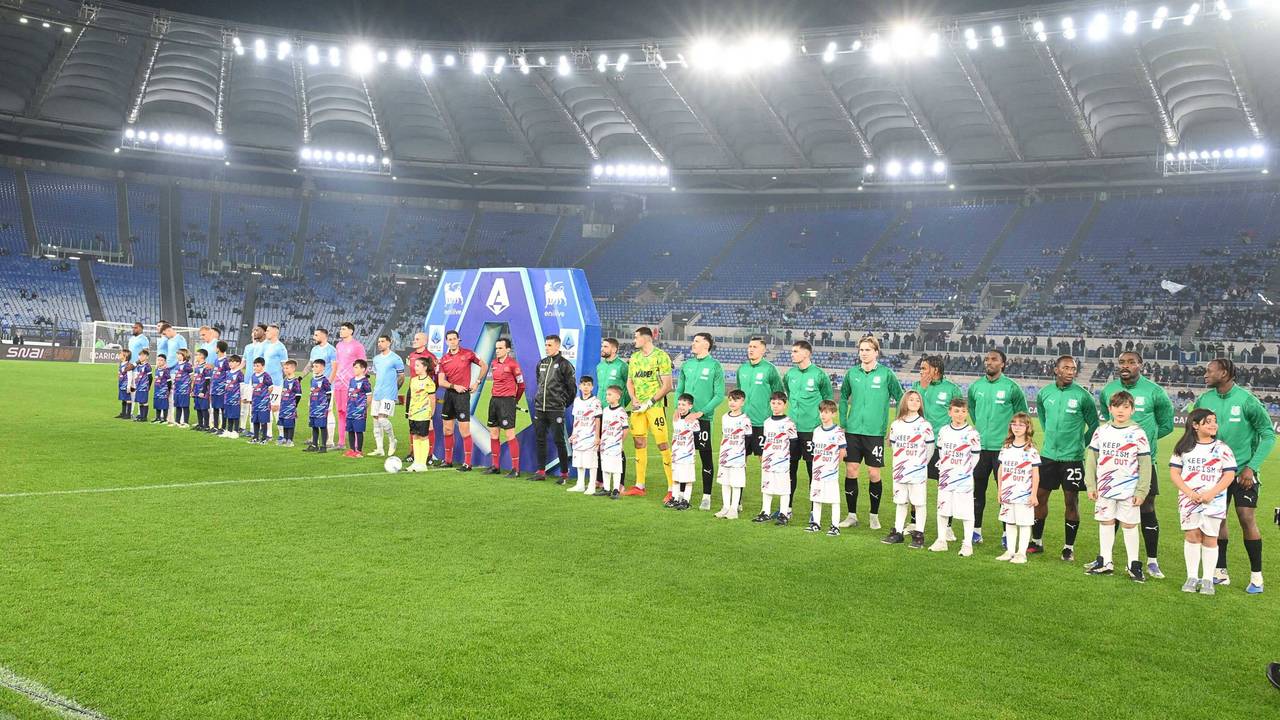Die Mannschaften stehen vor dem Spiel aufgereiht, auf der Tribüne dahinter sind kaum Fans.