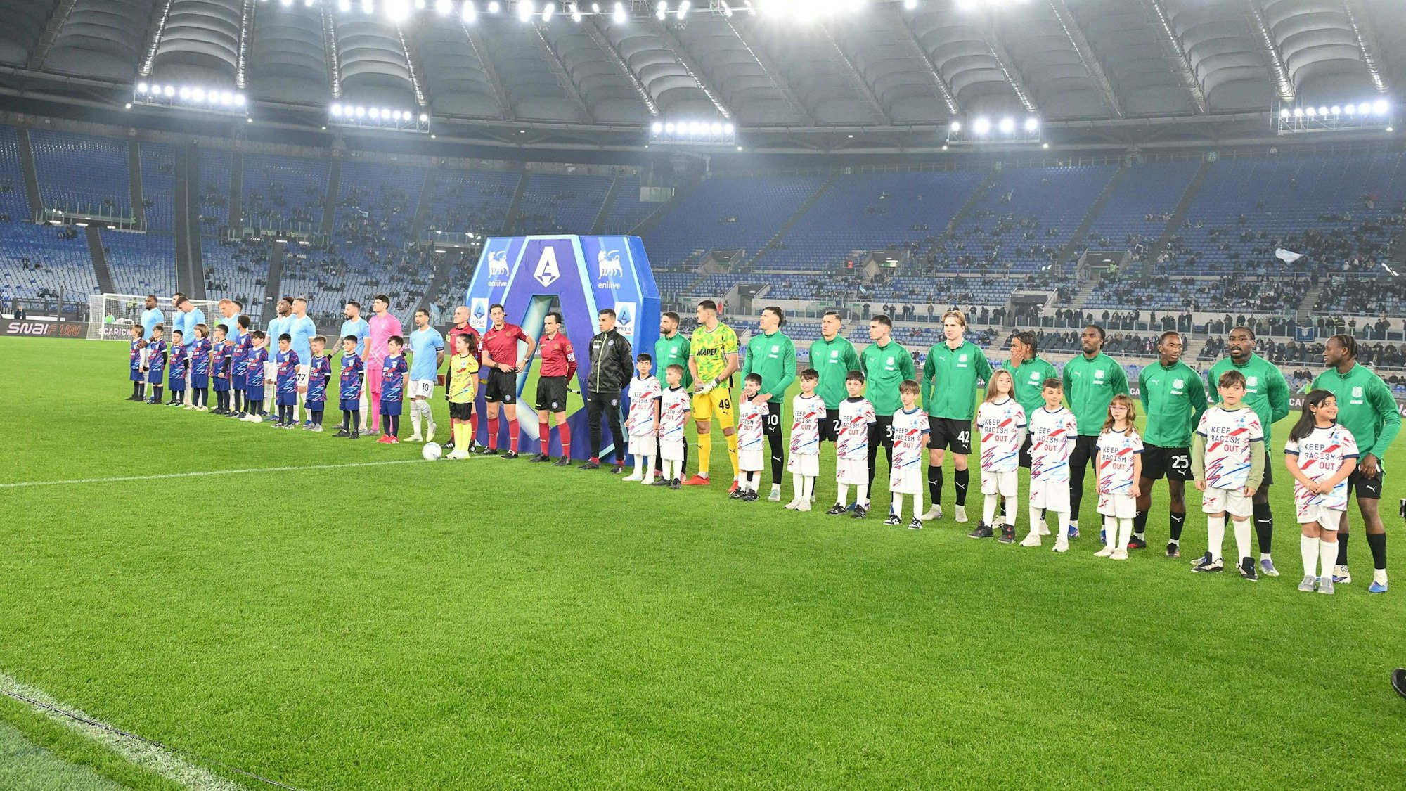 Die Mannschaften stehen vor dem Spiel aufgereiht, auf der Tribüne dahinter sind kaum Fans.