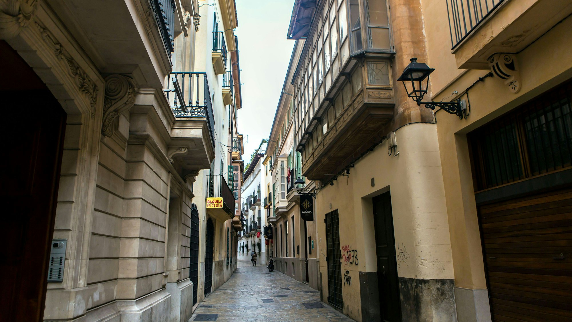 Enge Straße mit Gebäuden und wenigen Menschen