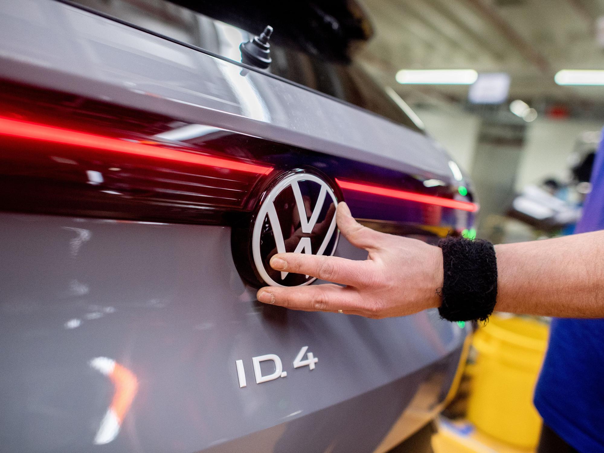 Ein Mitarbeiter setzt im Werk von Volkswagen das Logo der Marke an einem Fahrzeug vom Typ ID.4 ein. Der VW-Konzern präsentiert am Dienstag in Wolfsburg seine Bilanz für 2025.