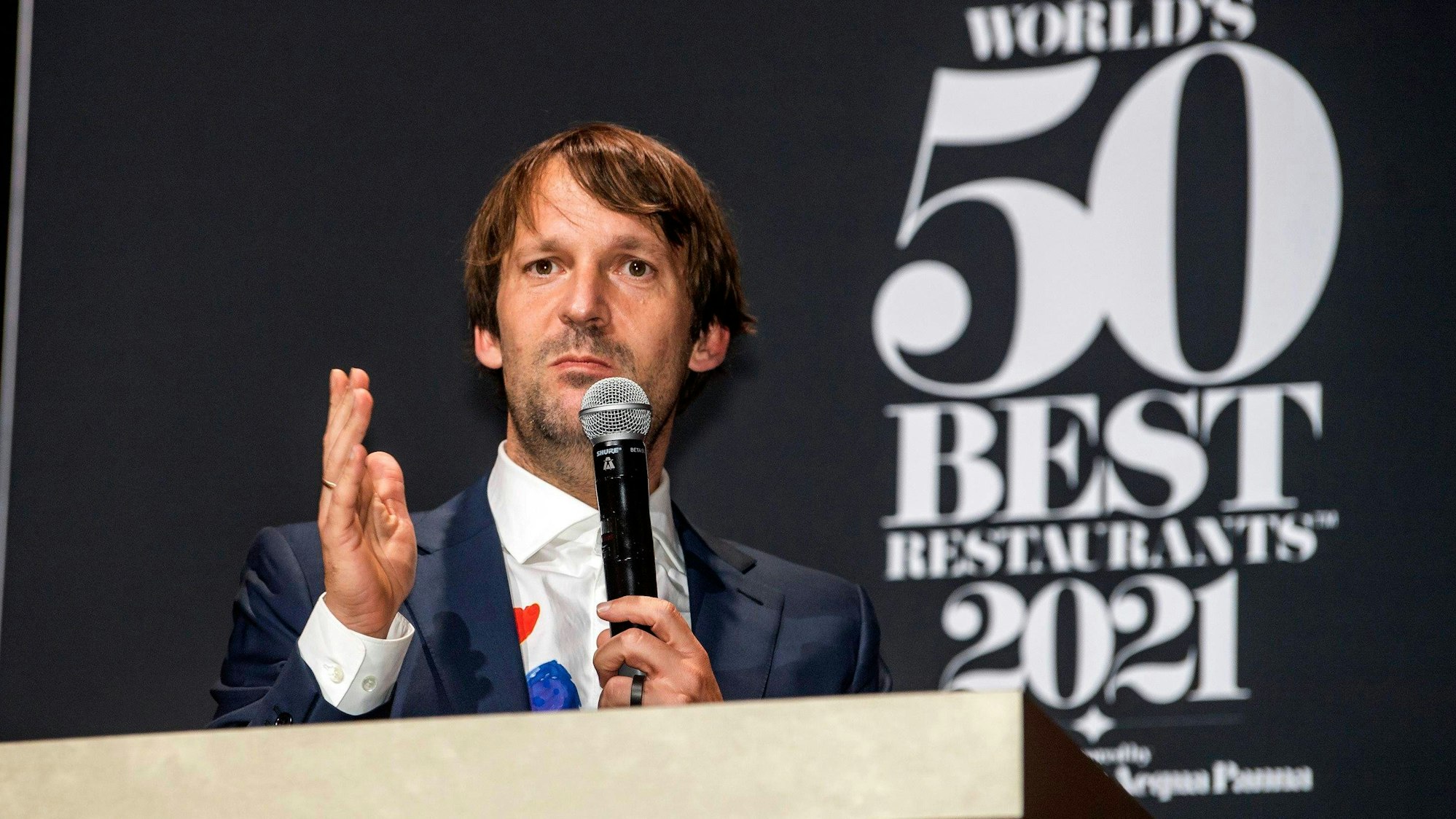 Rene Redzepi spricht am Mikrofon vor Hintergrundschriftzug