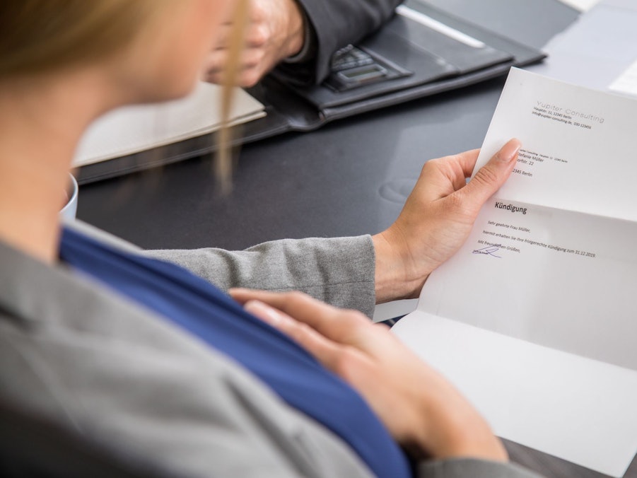 Eine schwangere Frau hält eine Kündigung in der Hand