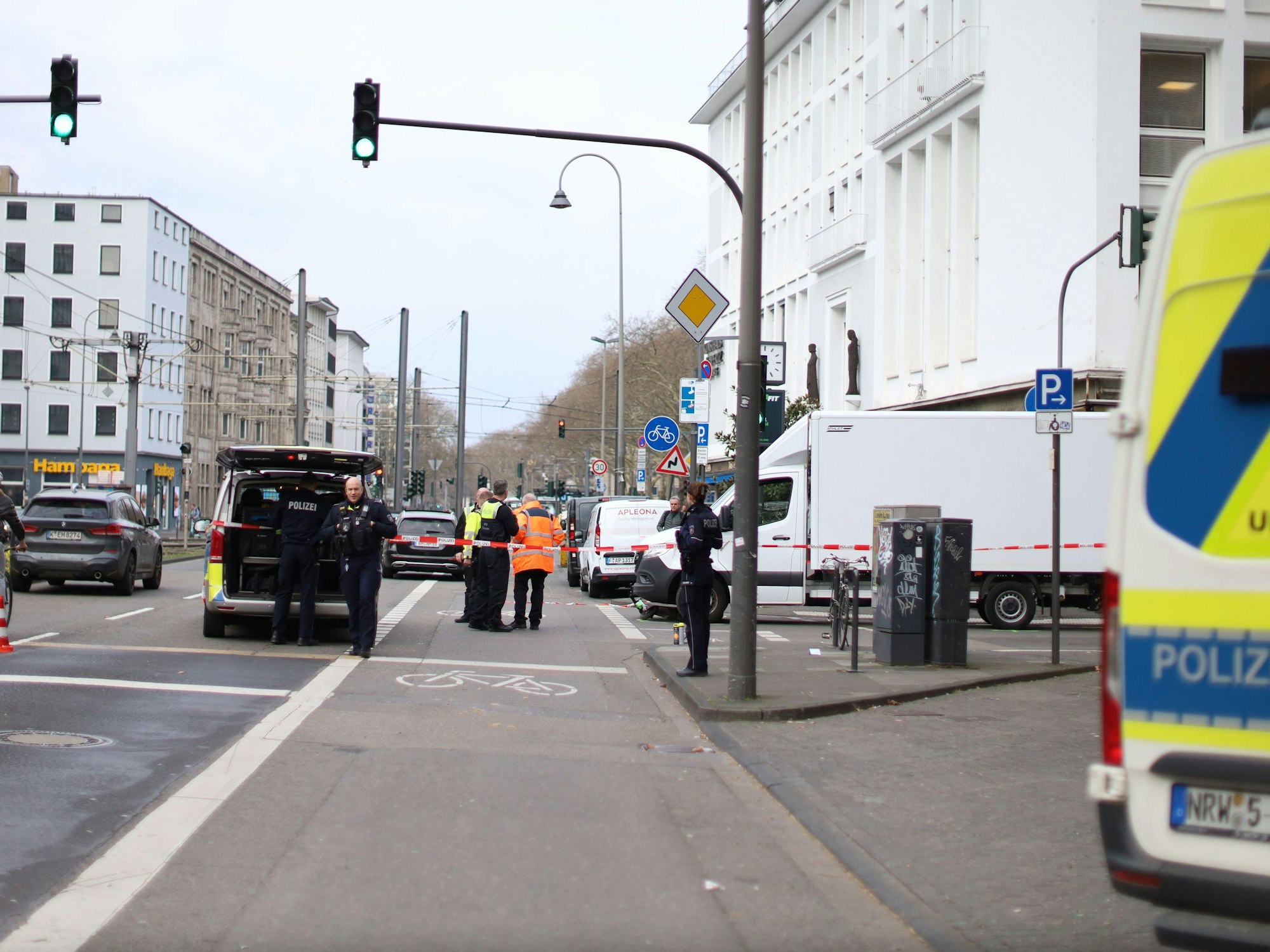 Polizeikräfte stehen auf der Straße, die teilweise abgesperrt wurde.