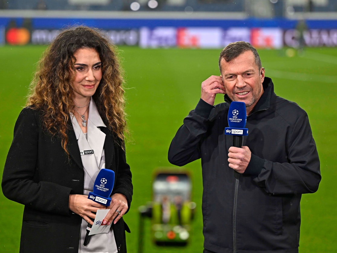 Lothar Matthäus an der Seite von Kimberly Budinsky mit Mikros in der Hand auf dem Rasen.
