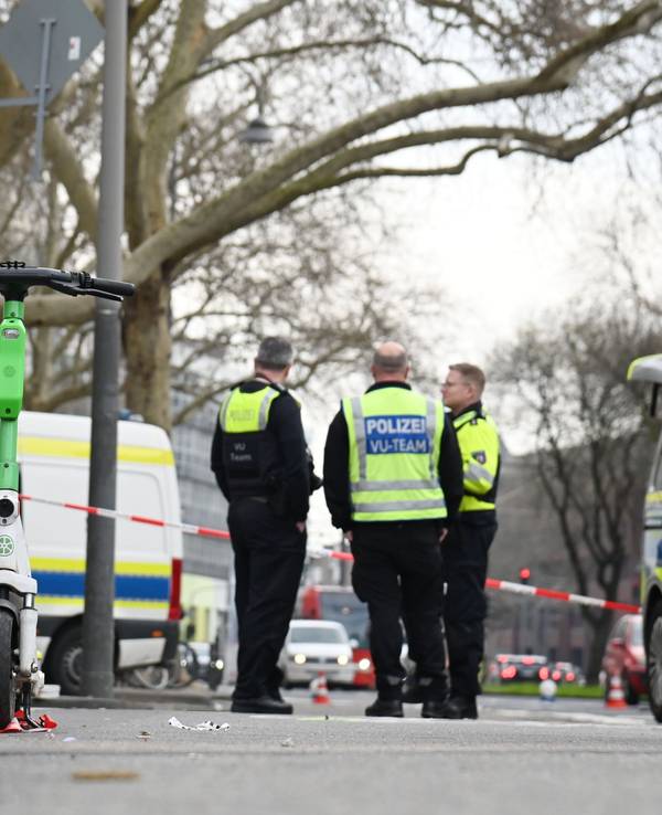 Polizeikräfte stehen an einer abgesperrten Straße.