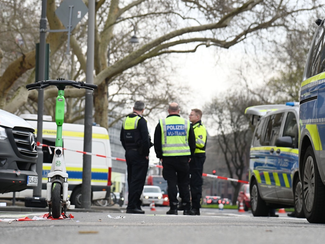 Polizeikräfte stehen an einer abgesperrten Straße.