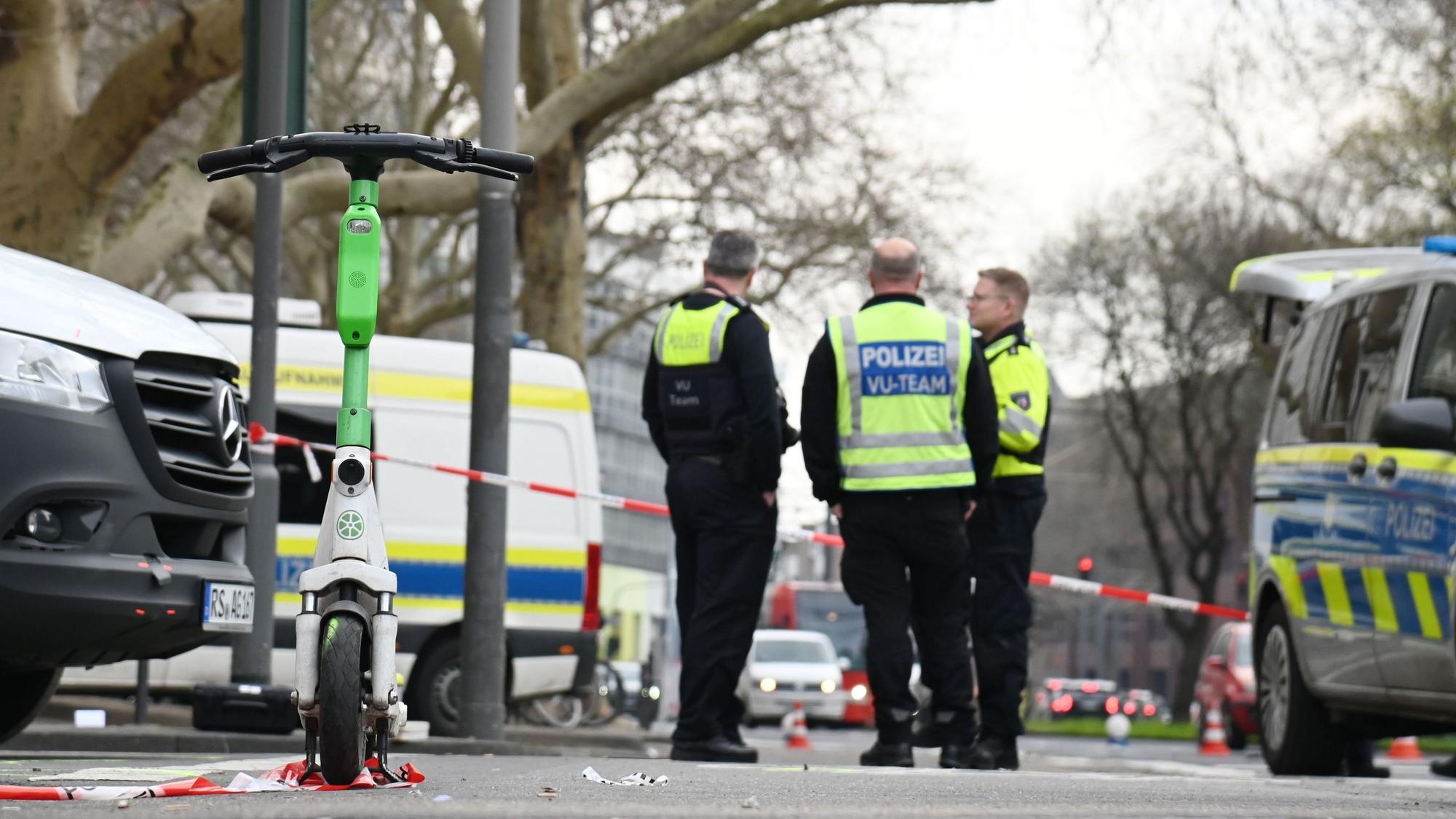 Polizeikräfte stehen an einer abgesperrten Straße.