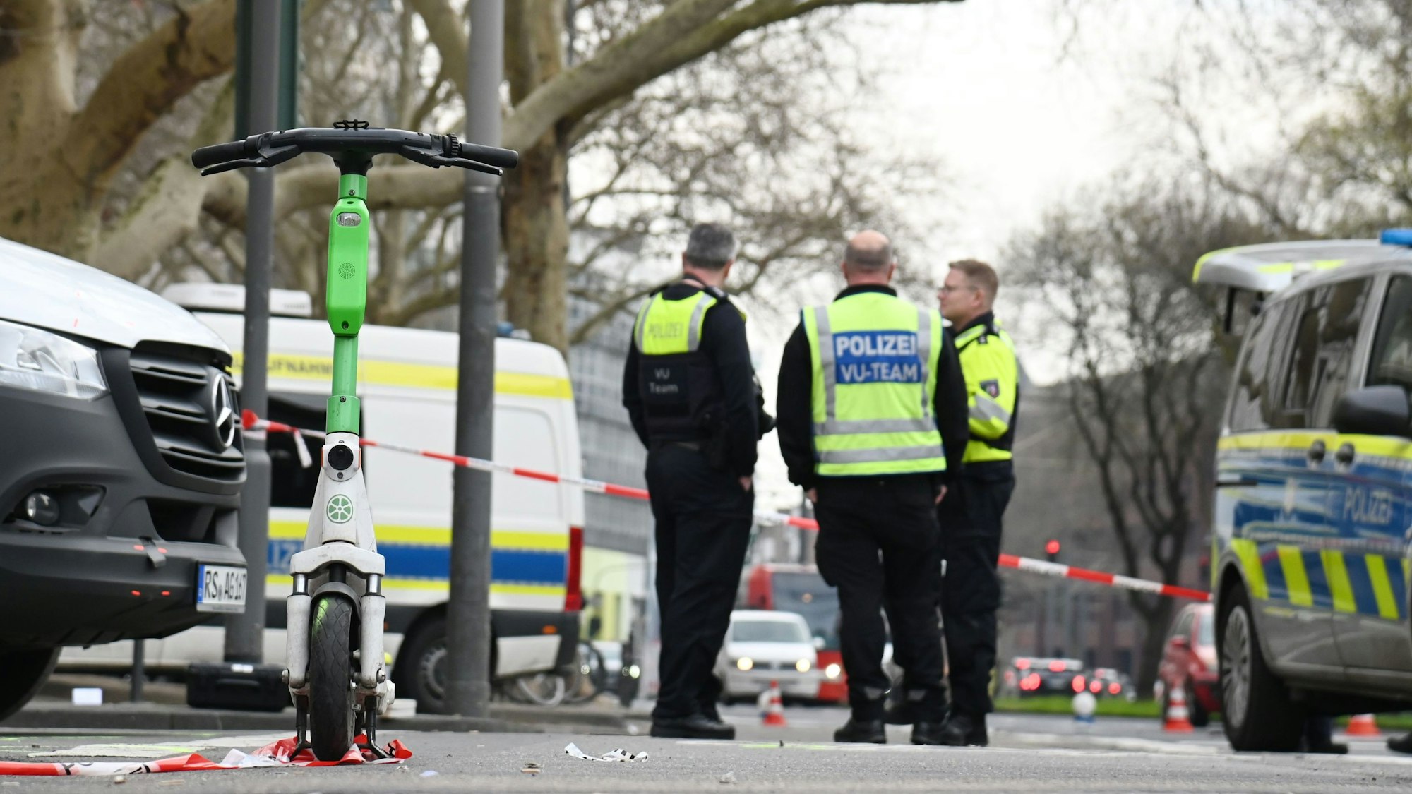 Polizeikräfte stehen an einer abgesperrten Straße.