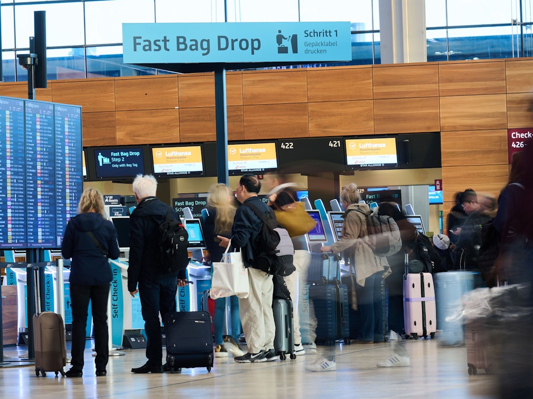 Menschen stehen mit Koffern an den Self Check-in Schaltern am Flughafen BER (Archivbild).