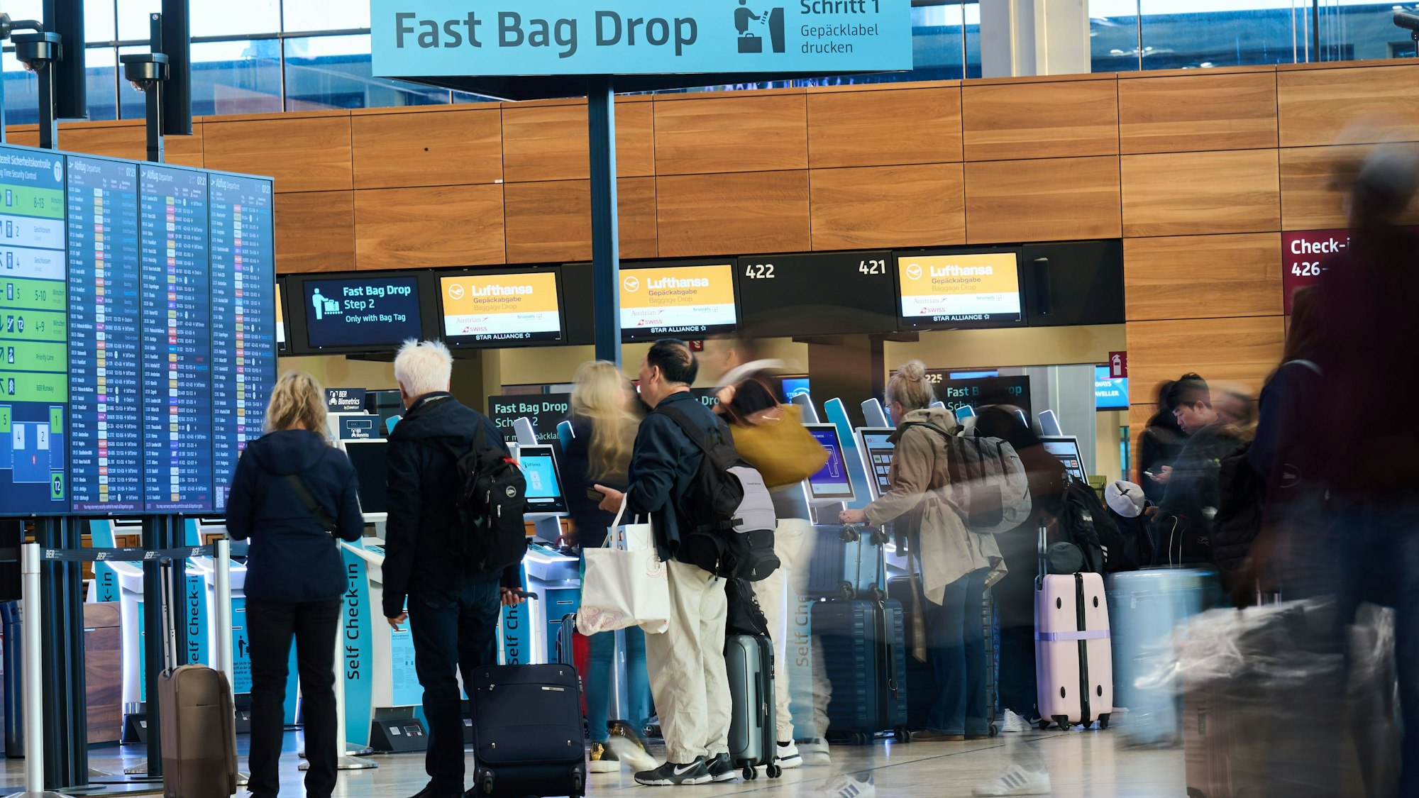 Menschen stehen mit Koffern an den Self Check-in Schaltern am Flughafen BER (Archivbild).