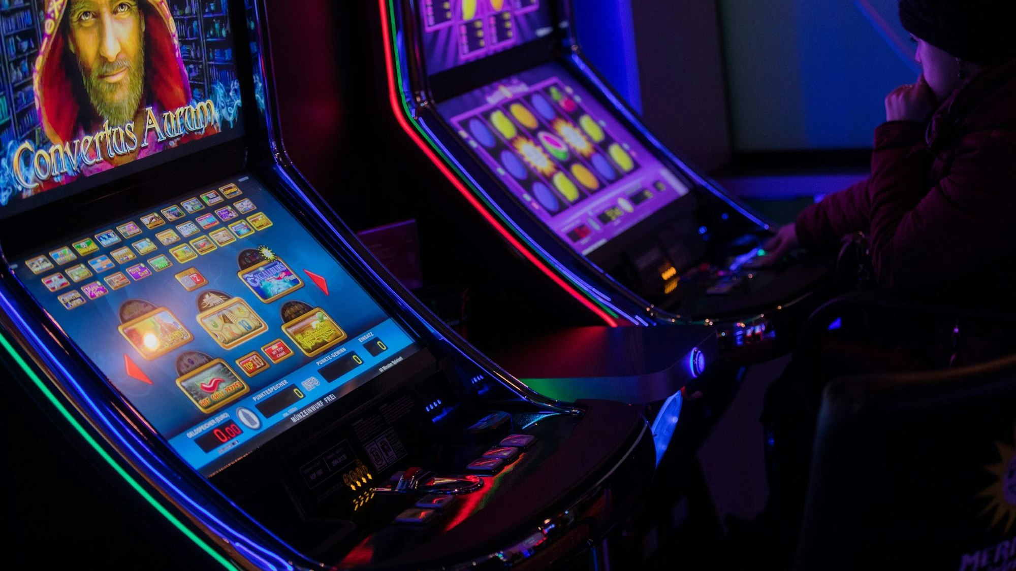Eine Person sitzt an einem Spielautomaten
