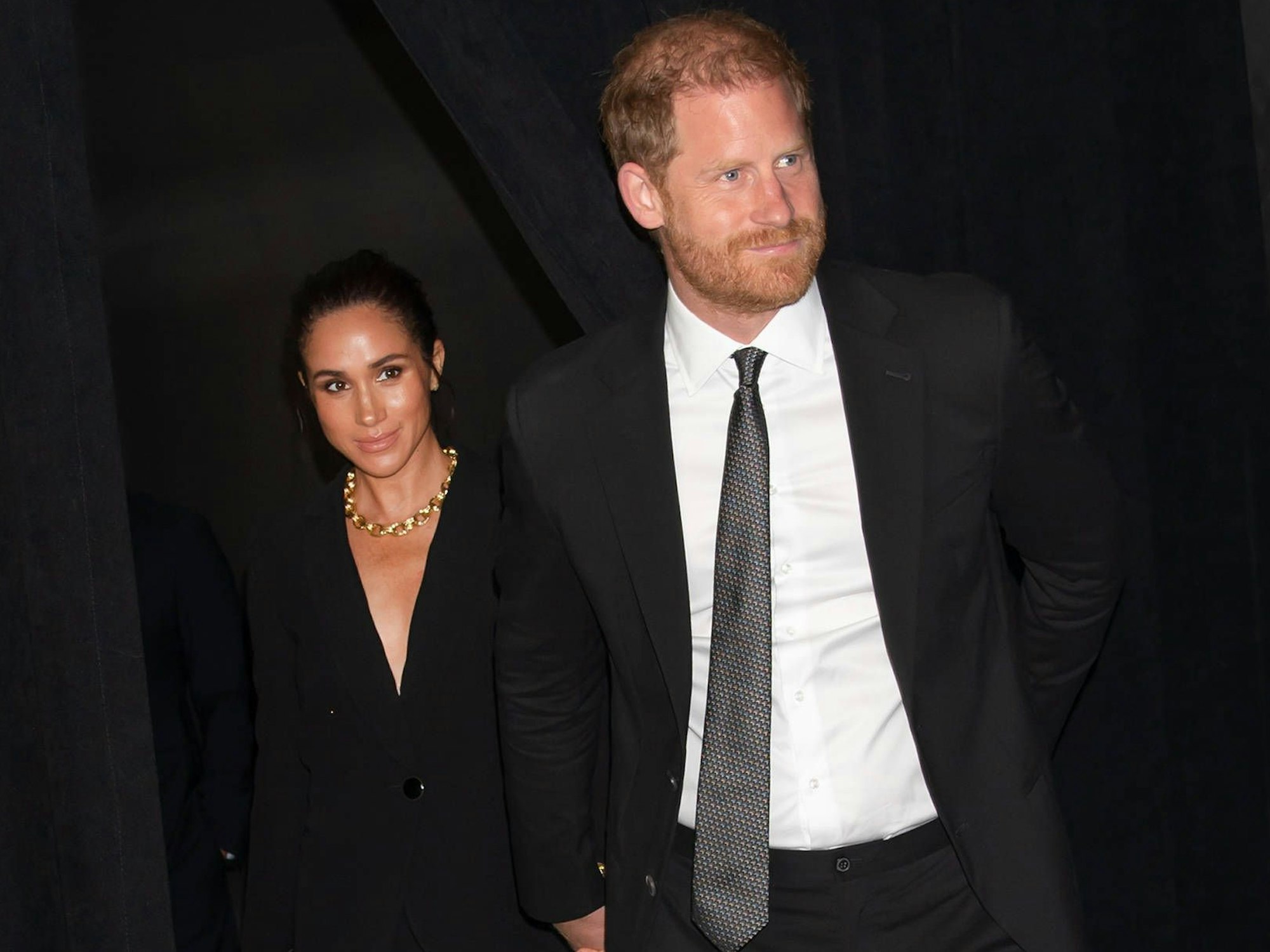 Meghan Markle und Prinz Harry gehen durch einen Vorhang.