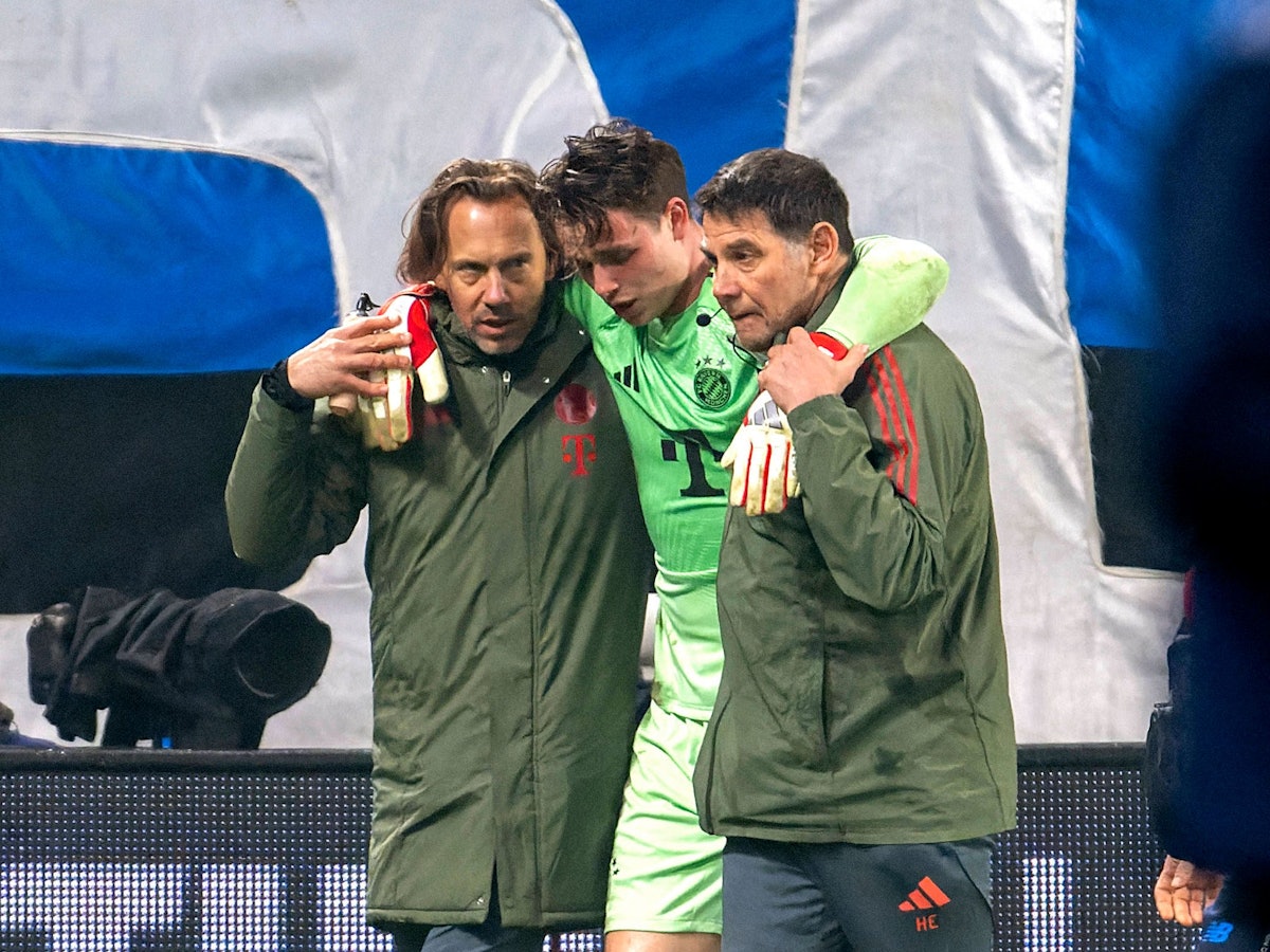 Jonas Urbig wird von zwei Bayern-Betreuern gestützt.