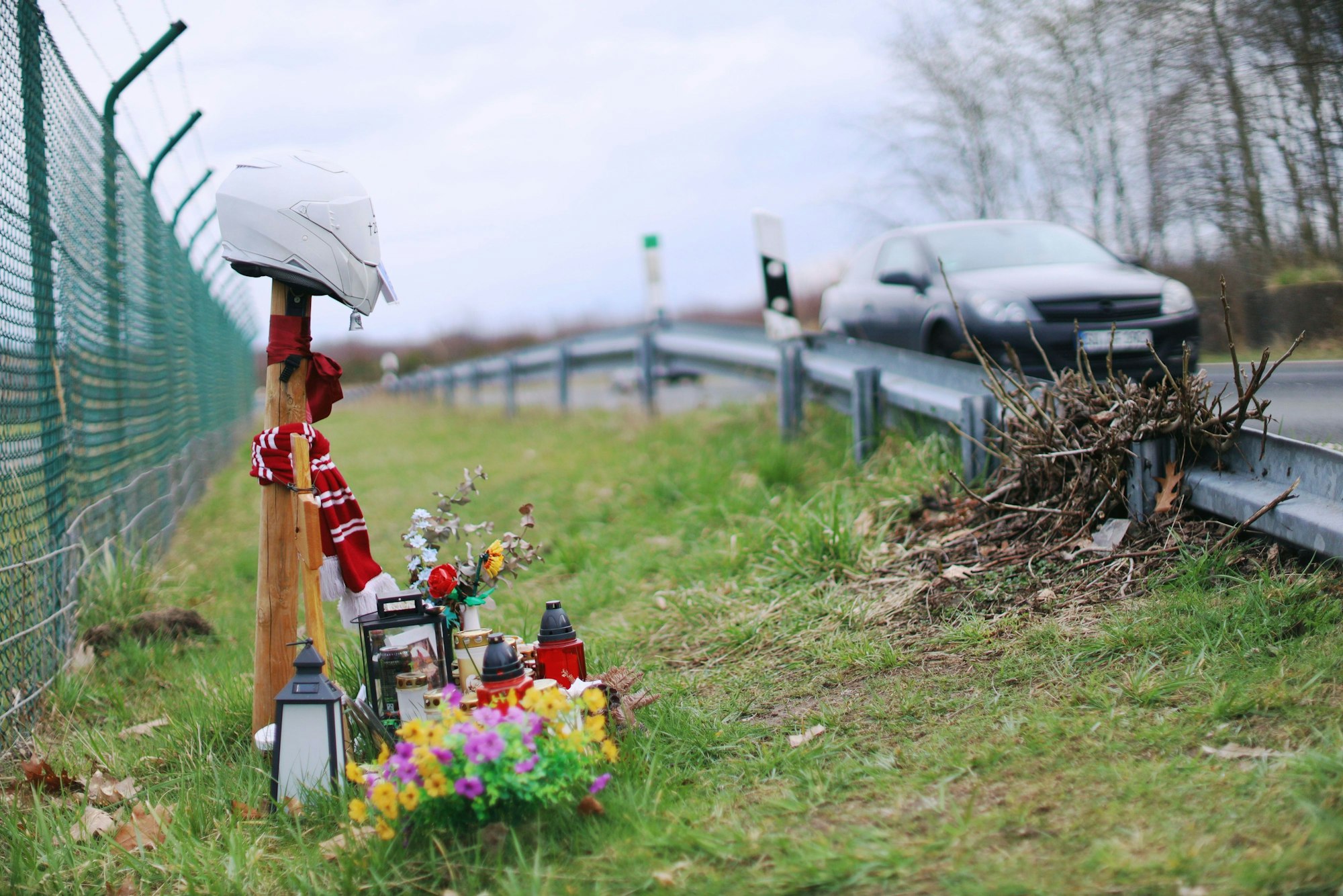 Auf der Alten Kölner Straße am Flughafen, wo im Sommer 2025 zwei junge Motorradfahrer bei einem tragischen Unfall starben, erinnert unter anderem ein Kreuz an eines der Opfer.