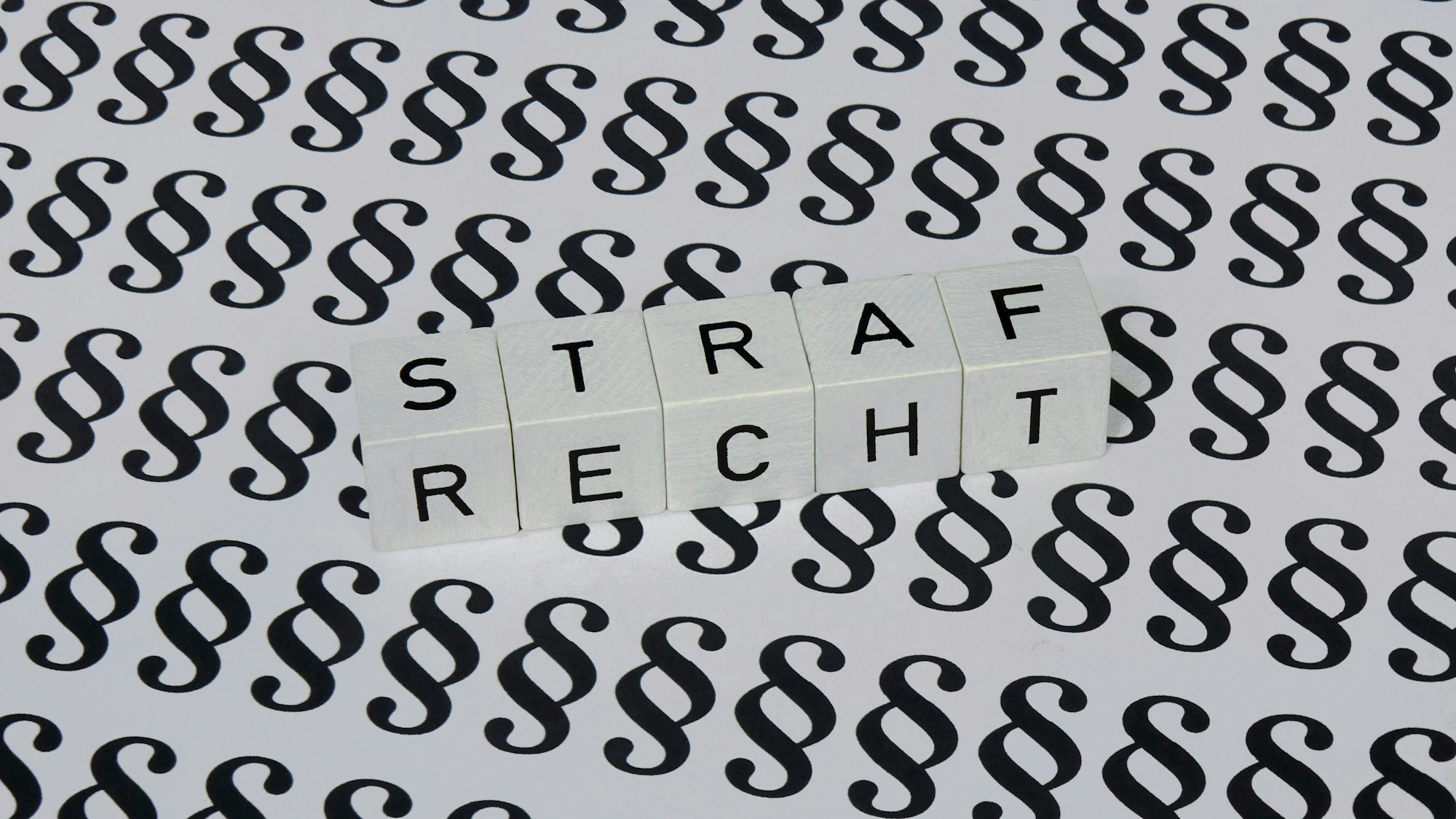 Paragrafen und Buchstabenwürfel mit „Strafrecht“