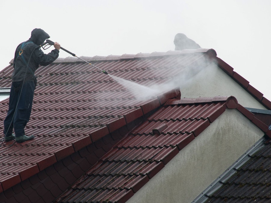 Arbeiter reinigen das Dach eines Hauses