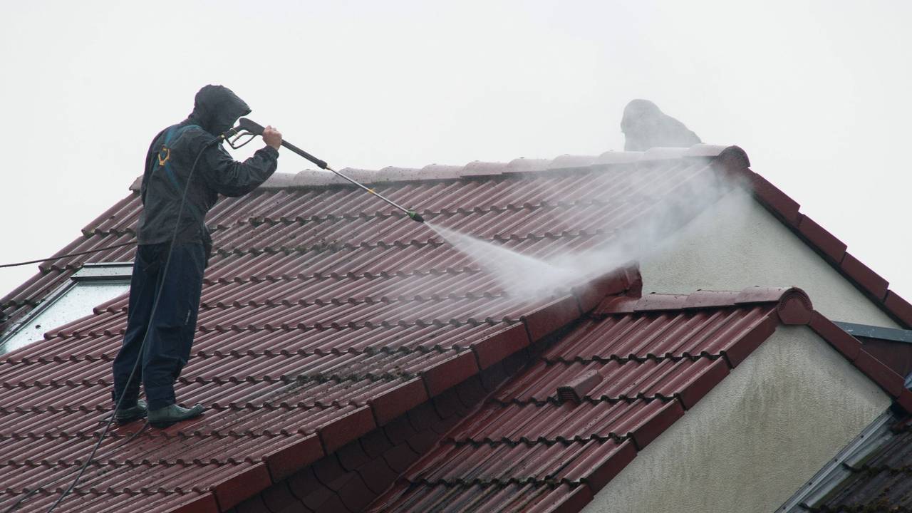 Arbeiter reinigen das Dach eines Hauses